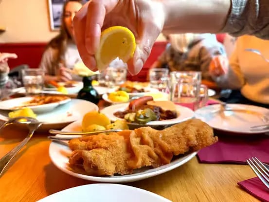 Squeezing fresh lemon over a crispy golden Wiener Schnitzel.