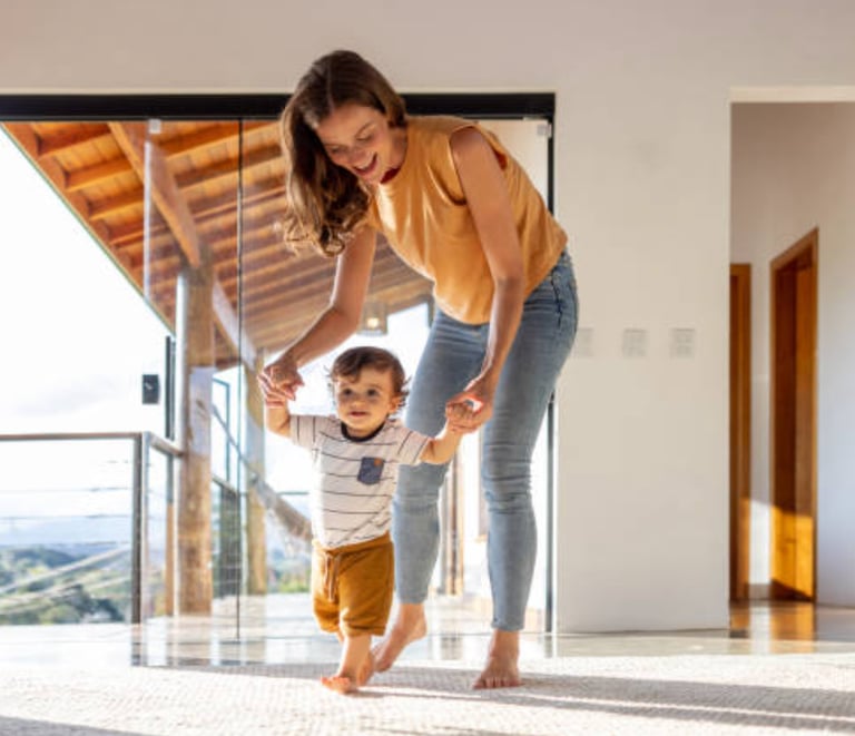 a woman holding a baby's hand while walking through a room martin pe coach de parejas