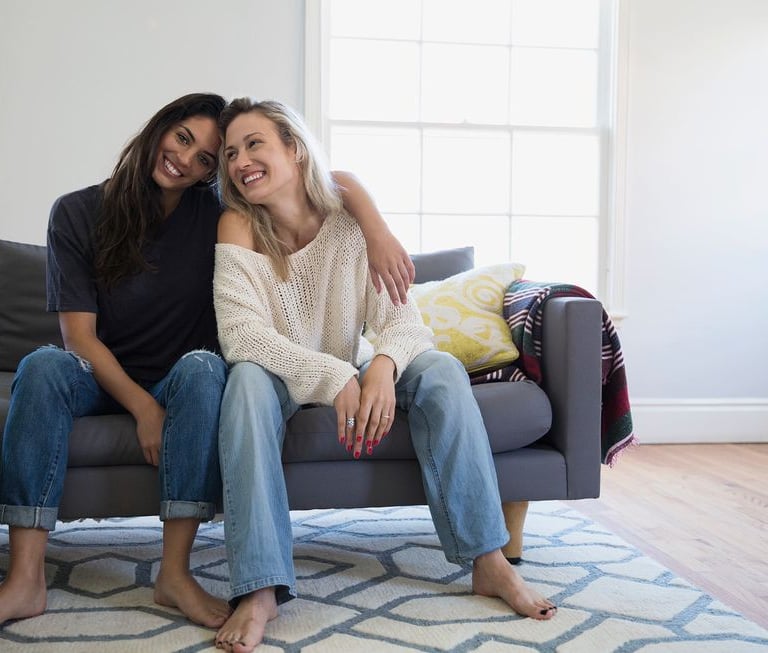two women sitting on a couch in a living room martin pe coach de parejas