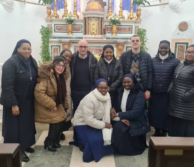 A group of Catholic nuns and several men and women posing for a photo inside a church in front of the altar.