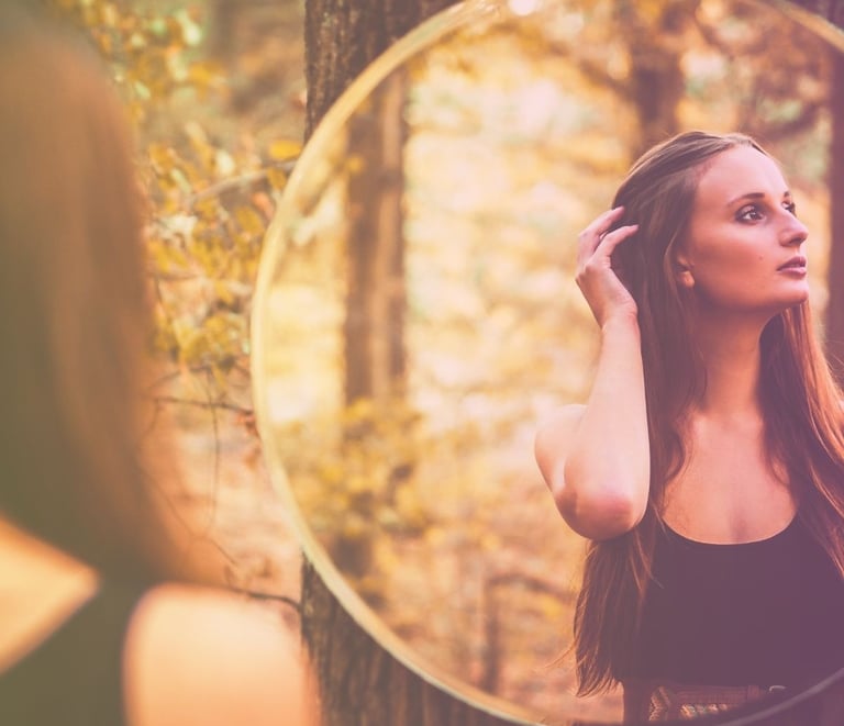 a woman in a black dress standing in front of a mirror