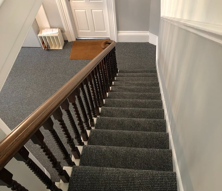 Dark grey carpet runner on stairs with a wooden banister in Worthing. 