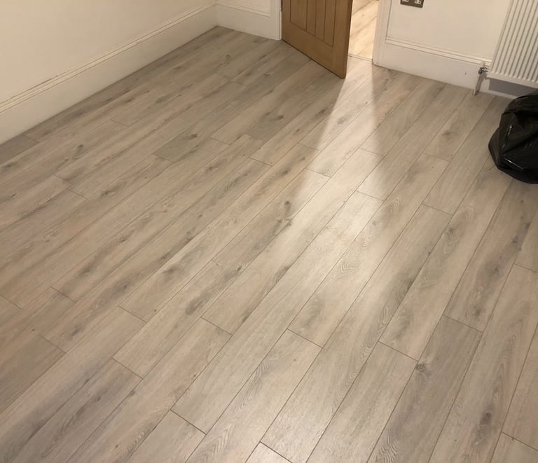 Modern grey oak laminate flooring installed in a Hove residential room with white skirting boards.