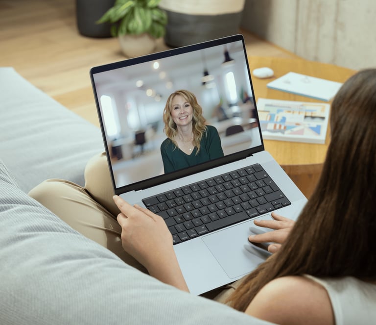 a woman sitting on a couch with a laptop computer screen showing a video chat with Gina Danford
