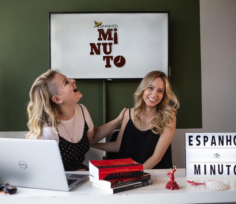 two women sitting at a desk with a laptop