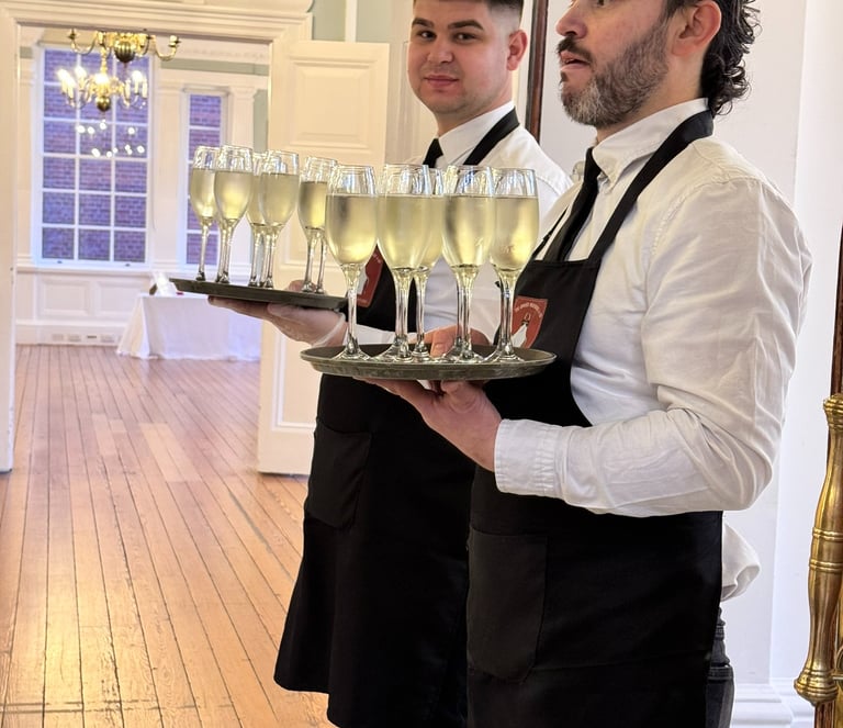 Waiter serving prosecco glasses at wedding bar hire reception