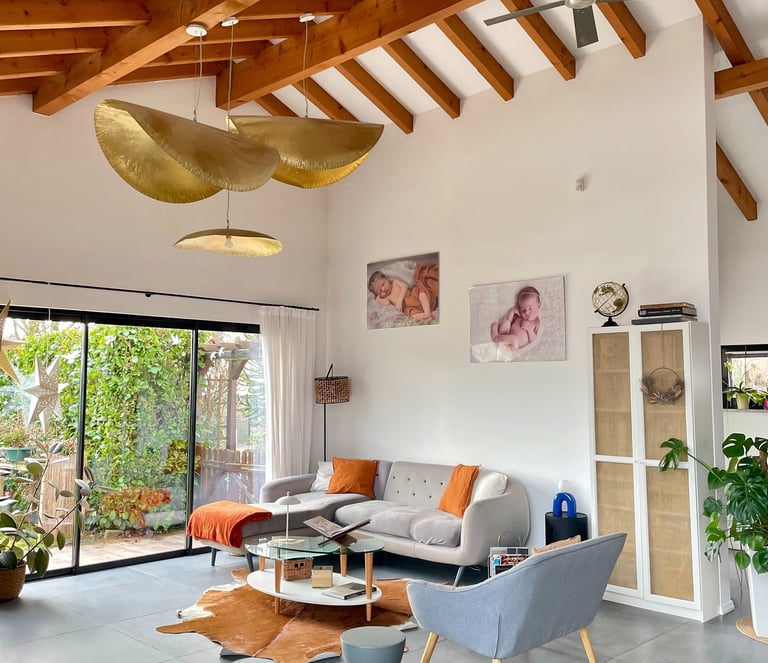 Modern living room with exposed wood ceiling beams, a grey sectional sofa, and gold leaf pendant lights.