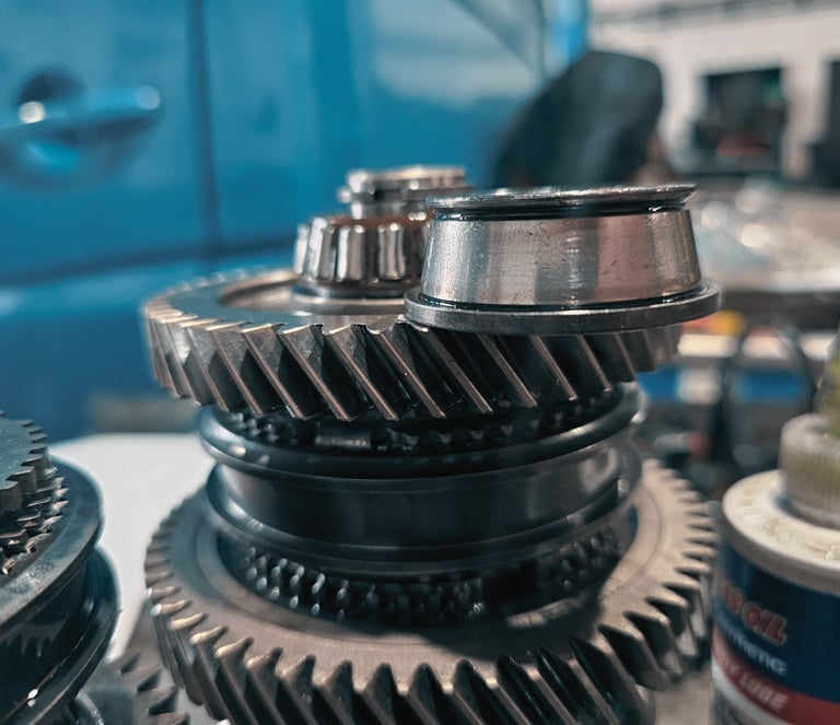 Close-up of metal transmission gears and mechanical components in an automotive repair shop.