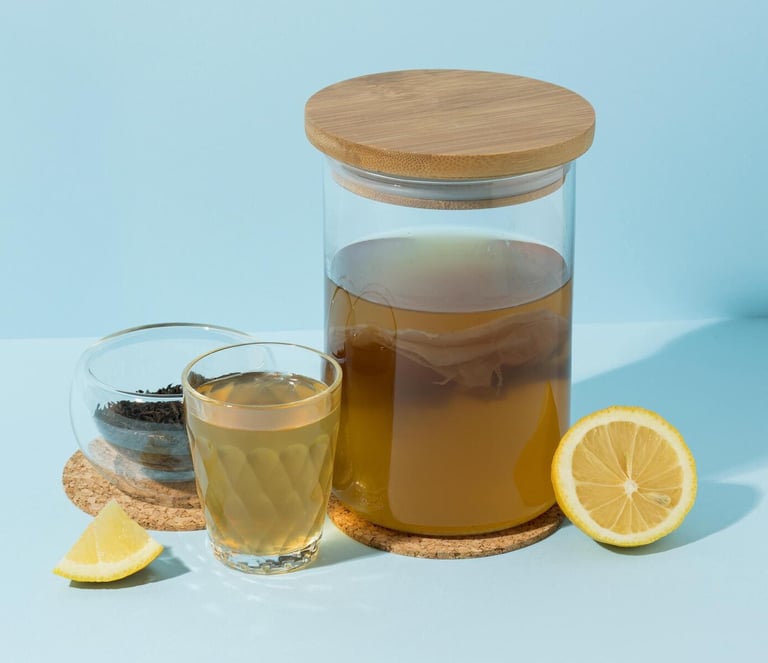 Té de kombucha casero en un frasco de fermentación de vidrio con SCOBY, limón fresco y especias.
