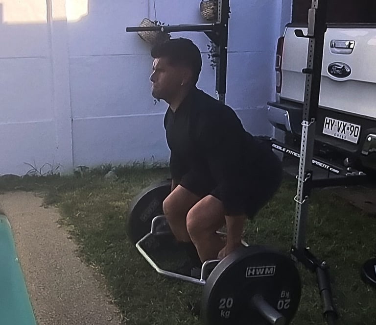 Cliente en peso muerto con barra hexagonal. Personal trainer a domicilio en La Reina.