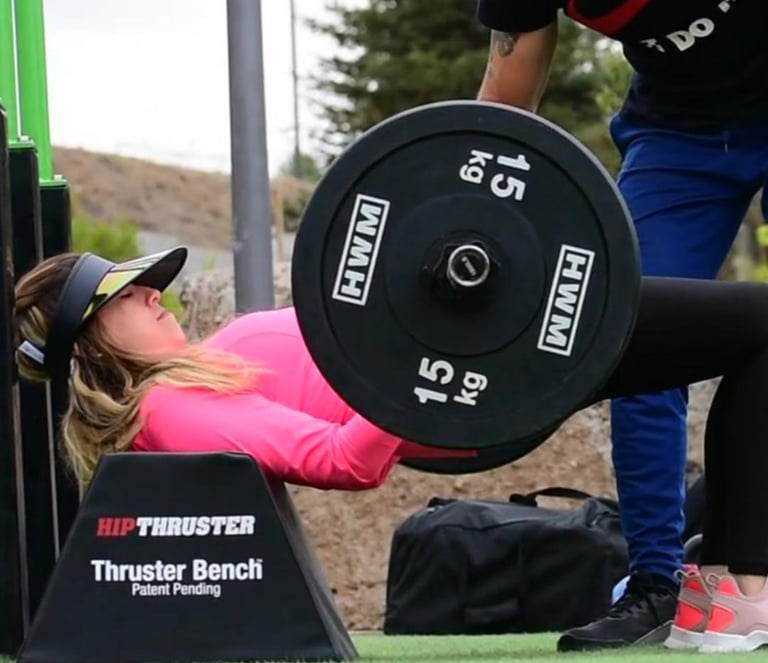 Entrenador ayudando a alumna para hacer hip thrust