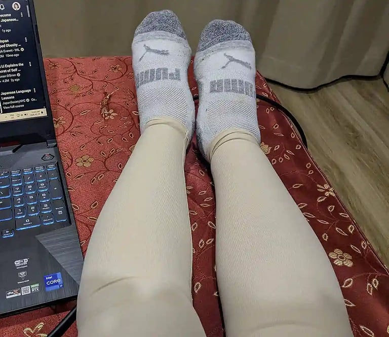 Leg compression sleeves during post surgery recovery with laptop nearby
