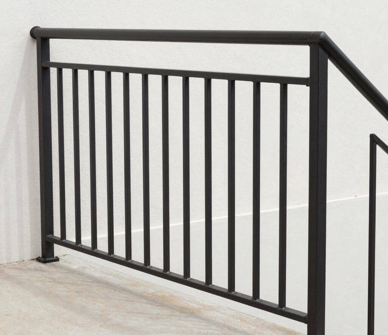 A welder focused on detailed railing fabrication, sparks flying gently in a workshop setting.