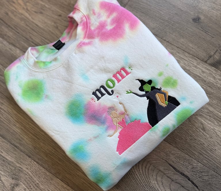 a white, pink and green tie dyed sweatshirt with the word "mom" embroidered on it
