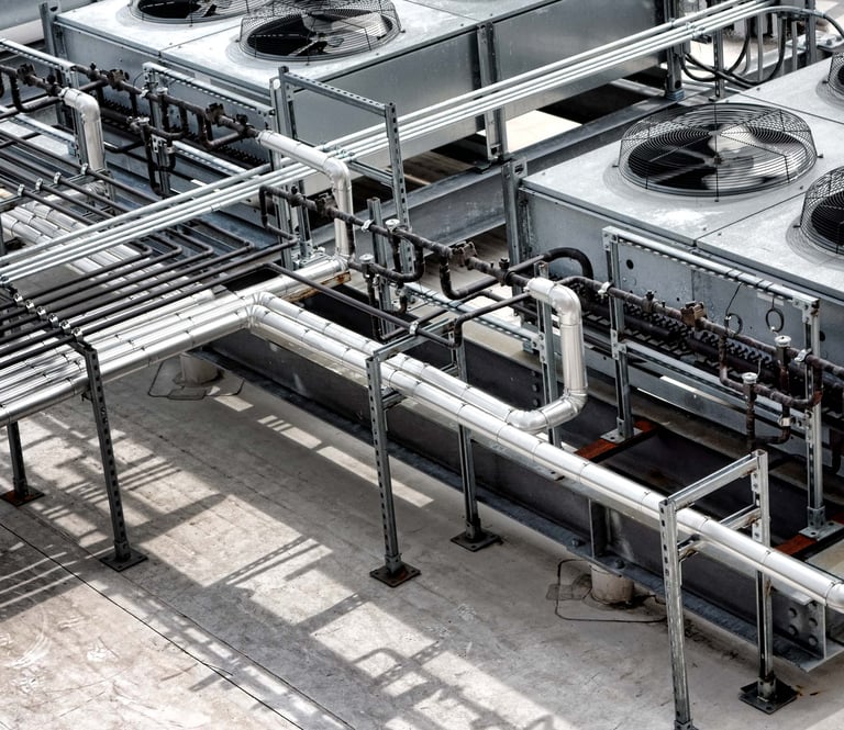 Industrial rooftop refrigeration gas coolers system with large fans and complex steel piping.