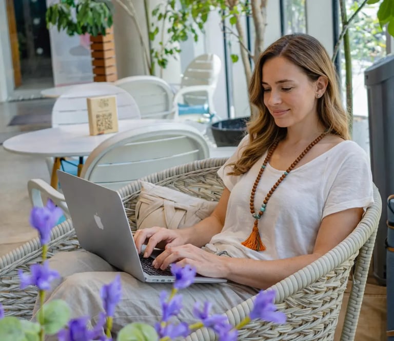 a woman sitting in a wicker chair with a laptop