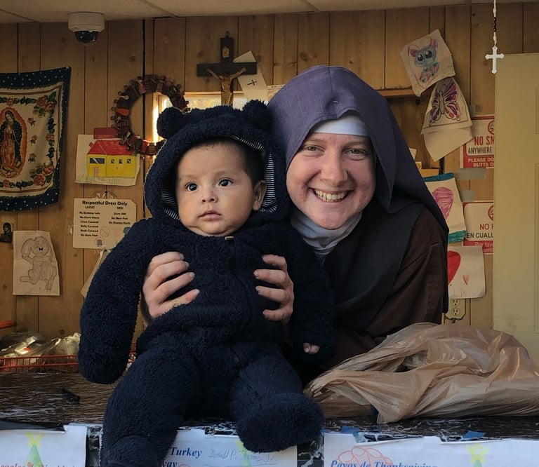 A Franciscan Daughter of Mary and a very cute baby pose for a picture at the Rose garden Mission