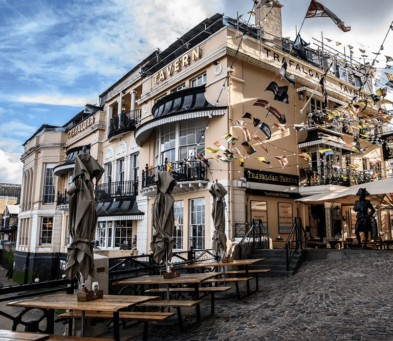 The historic Trafalgar Tavern in Greenwich London featuring outdoor seating and nautical flags.