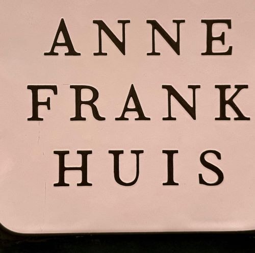 The official Anne Frank Huis museum sign featuring bold black serif typography on a light background.