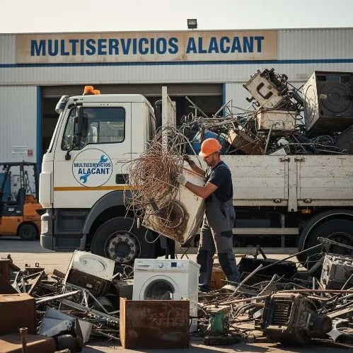 Trabajador recogiendo chatarra delante de la oficina de Multiservicios Alacant, cargando el camión