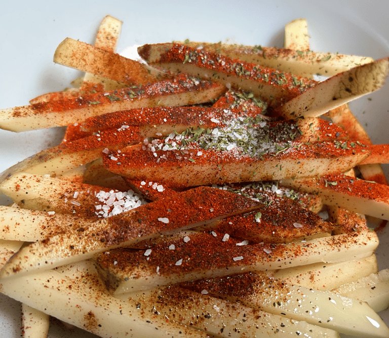 Raw potatoes with seasoning dumped ontop, not mixed yet. See ingredients list for details.