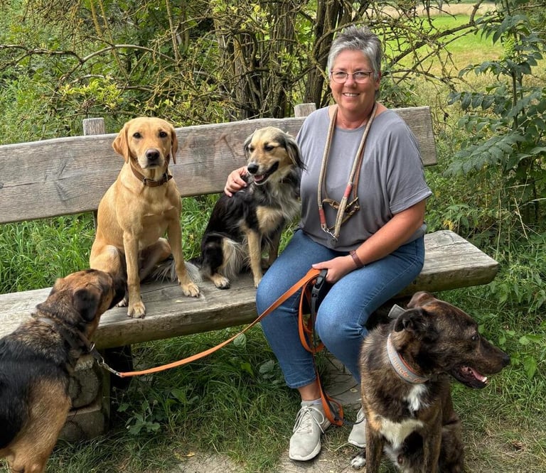 Marion Lindhof sitzt mit ihren Hunden im Park auf einer Bank.
