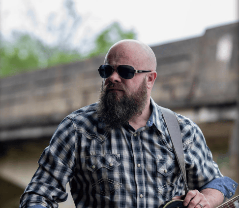a man with a beard and sunglasses on a guitar