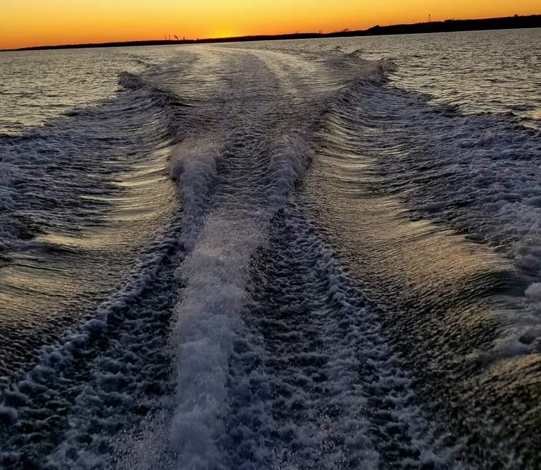 Pretty boat wake beneath a colorful sunset.