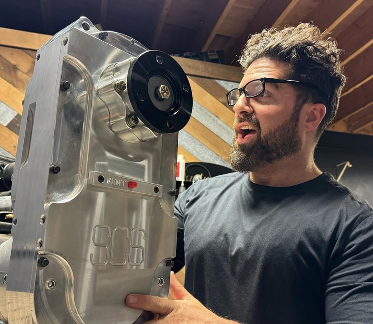 don abenante holding a high-performance SCS gear drive transfer case in a workshop.
