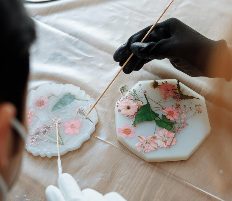 persona poniendole detalles de flores secas a una pieza de resina.