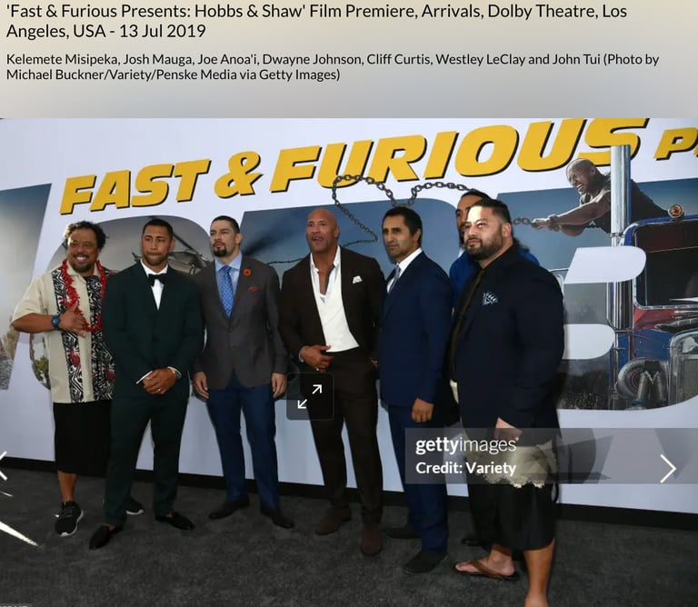 Dwayne Johnson with John Tui  in front of a fast & furious backdrop billboard 