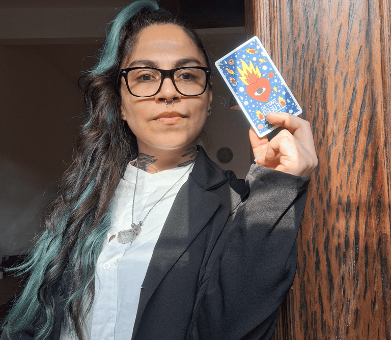 Mujer con lentes sosteniendo una carta de tarot con un corazón en llamas