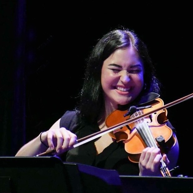 Musician Evelyn Thom smiling with her eyes closed while playing the fiddle.