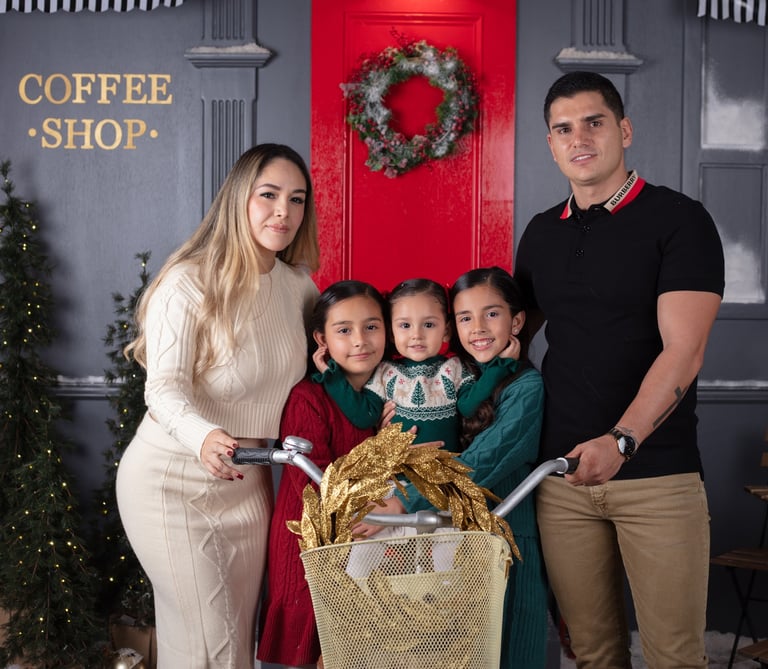 una familia de 5, mamá, papá y 3 hijas en un set navideño