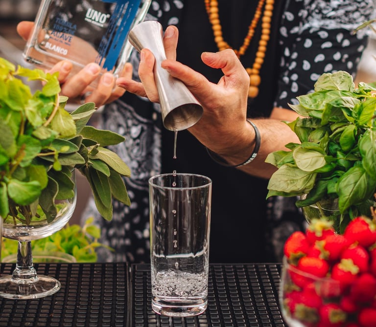 a man is pouring tequila into a glass with in the back a bottle of uno tequila blanco 