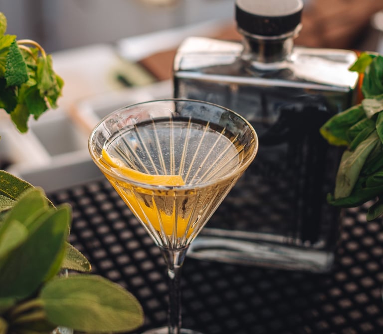 a martini glass with a tequila cocktail in it with in the back a bottle of uno tequila cristalino