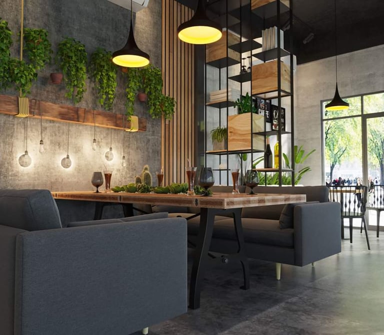 Modern cafe interior with industrial decor, hanging plants, wooden tables, and grey sofa seating.