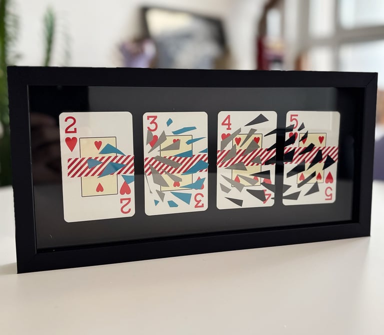 imagem da obra, composta por 4 cartas de baralho com intervenções de washi tape e fita isolante, emolduradas com fundo preto.