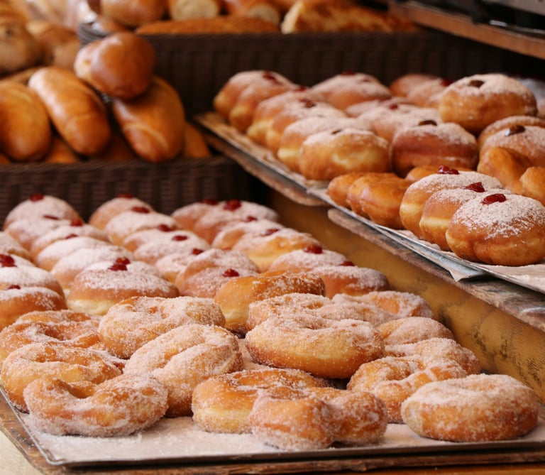 Donuts recién hechos recubiertos de azúcar y rellenos de mermelada expuestos en el mostrador