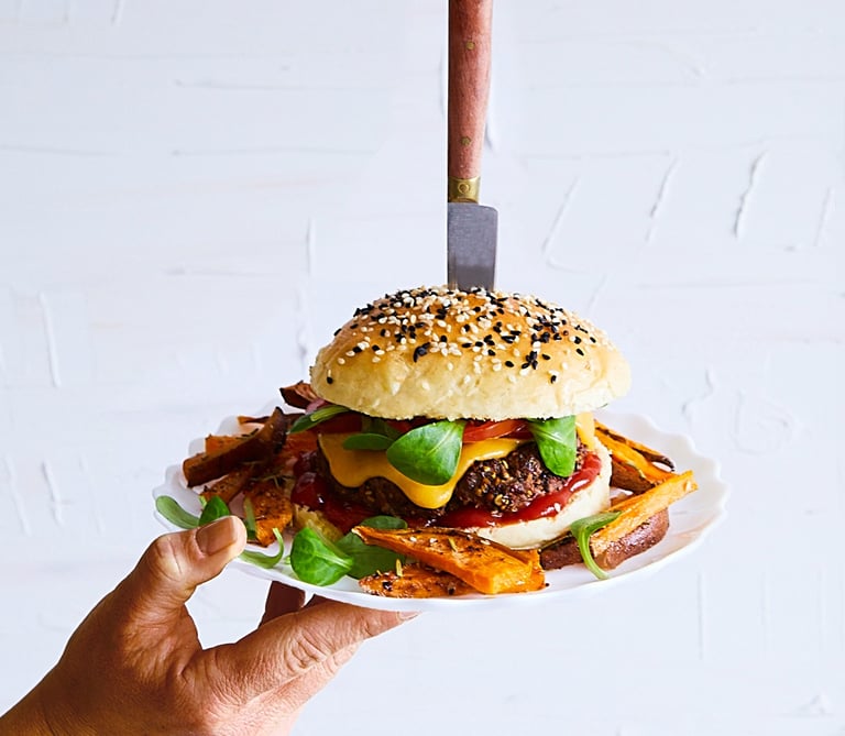 a person holding a plate with a hamburger burger on it
