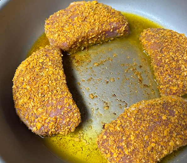 Battered pork chops starting their sear in pan