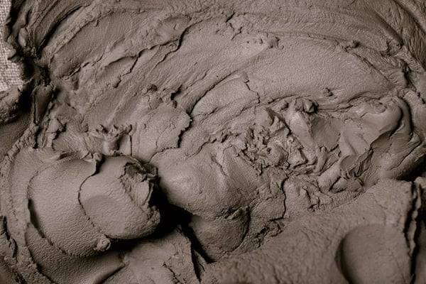 Close-up of thick, textured natural grey clay used for pottery and therapeutic facial masks.