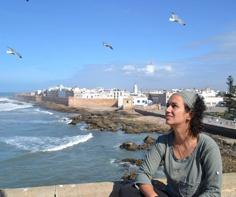a woman sitting on a ledge looking out over the ocean beatriz alvarez