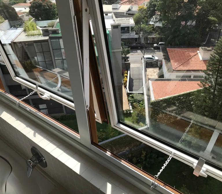 Trava de segurança com corrente limitadora instalada em janela de banheiro sobre a caixa acoplada