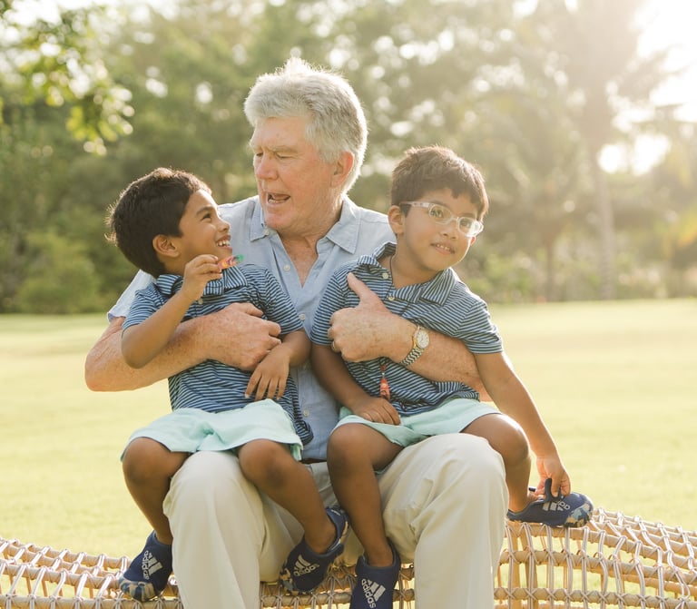 grandfather sitting and hugging his grandchildren on a woven chair at rimba by ayana bali during relaxed family photography