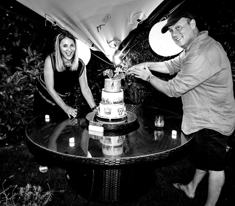 a man and woman cutting a cake with candles