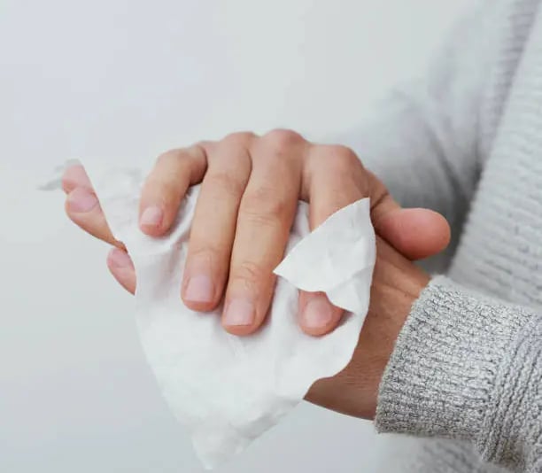 a person cleaning his hands with a wet tissue towel