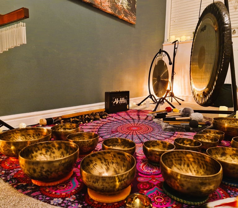 Shruti box, chimes, gongs, and many singing bowls arranged on a mat