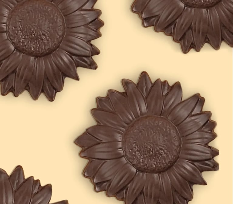 Dark chocolate sunflower shaped candies arranged on a pale yellow background.
