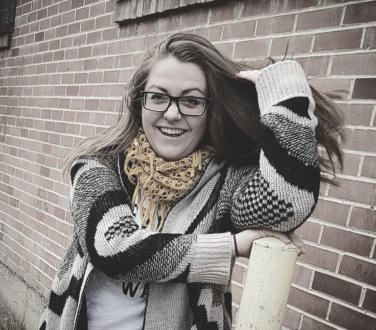 photo of sara dudenhoeffer dressed in a sweater and scarf, laughing